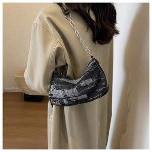 Détail du sac hobo texturé noir et blanc avec bandoulière chaîne porté par un mannequin