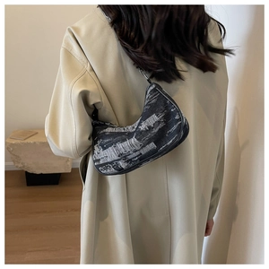 Détail du sac bandoulière en toile grise avec franges porté sur manteau beige