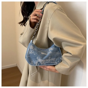 Détail du sac sous l'aisselle en denim bleu clair avec chaîne argentée sur l'épaule