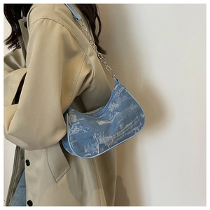 Detail of light blue denim crescent underarm bag with bleached marble pattern print