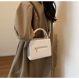 Detail of white crocodile pattern handbag with golden zipper and sturdy handle