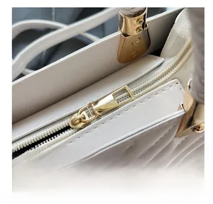 Close-up of smooth gold zipper and hardware on cream minimalist small square bag