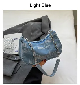 Close-up of light blue denim underarm bag with silver chain on white background