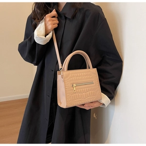 Detail of beige crocodile pattern bag featuring gold zipper and PU leather texture