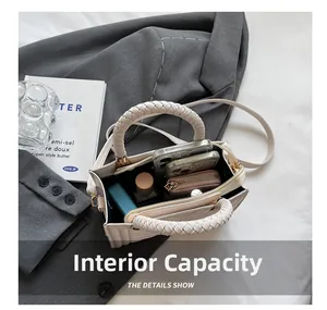 Detail view of the interior capacity showing a wallet, phone, and lipstick inside the bag