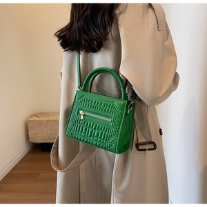 Bright green crocodile pattern handbag worn with a beige trench coat for a trendy autumn look