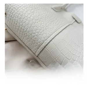 Detail of white crocodile pattern leather tote bag showing high-quality stitching and handle