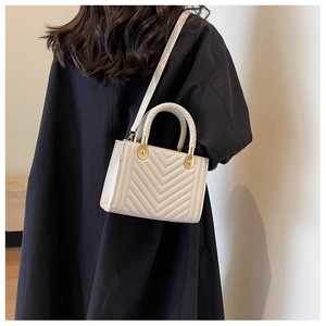 Rear view of a model carrying a white V-quilted handbag with gold hardware details