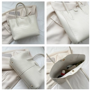 Detail view of white crocodile embossed tote bag with gold studs and spacious interior