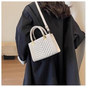 Detail of off-white chevron quilted handbag with woven handles and gold hardware accents