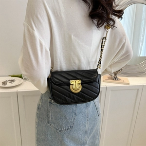 Classic black quilted shoulder bag with gold T-lock shown on model in a modern room