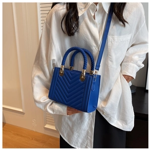 Royal blue quilted handbag with woven handle and gold hardware on model