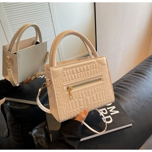 Detail of creamy white crossbody bag showing croc texture and golden hardware