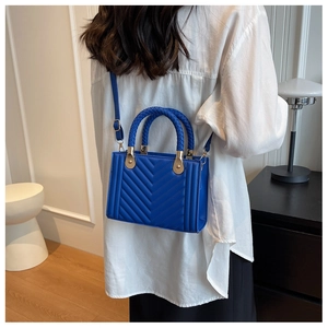Royal blue handbag with chevron quilting and woven textured handles on a model