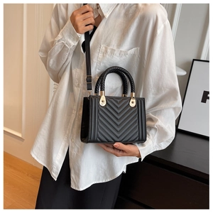 Close-up of black quilted leather handbag with woven handle and gold hardware detail