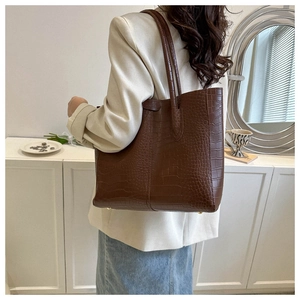 Detail of dark brown tote bag featuring elegant crocodile embossed texture and long straps