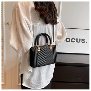 Detail of black chevron quilted crossbody bag with woven handle and gold hardware