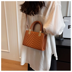 Detail of caramel brown quilted shoulder bag with woven handle and gold hardware