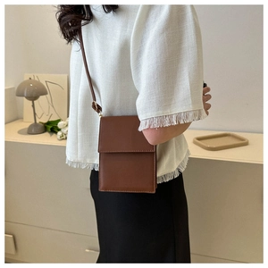 Detail view of brown PU leather crossbody bag featuring minimalist flap design and stitching