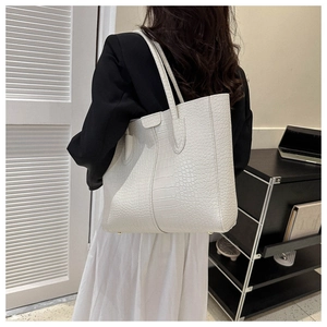Detail shot of white crocodile embossed tote bag worn over the shoulder for commute