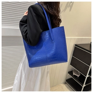 Detail of royal blue tote bag with crocodile texture and protective gold base studs