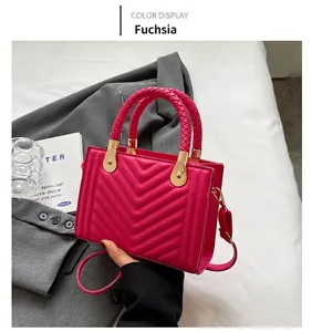 Detail of rose red crossbody bag featuring V-shaped quilting and golden metal buckles