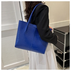 Detailed view of Klein blue tote bag with embossed crocodile texture and gold metal base