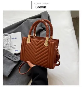 Detailed view of brown quilted handbag with braided handle and gold hardware accents