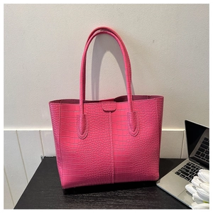 Close-up of rose pink crocodile pattern tote bag on a desk with a laptop