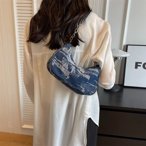 Sac sous le bras en denim rétro avec chaîne argentée porté par un mannequin en studio