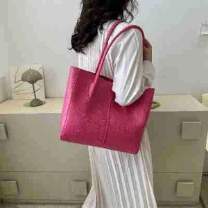 Hot pink minimalist tote bag with textured surface shown on model for casual commuting style