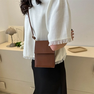 Minimalist brown leather rectangular crossbody bag for women in a stylish home setting