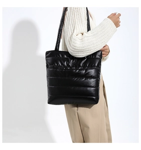 Close-up of a stylish black quilted tote bag with a high-gloss finish and puffy texture