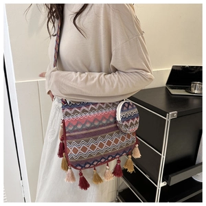 Détail du sac bandoulière en tricot géométrique avec pompons et mini porte-monnaie