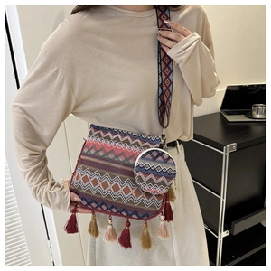 Gros plan sur un sac à bandoulière ethnique tissé avec motifs géométriques et glands