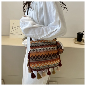 Détail du sac bandoulière tissé bohème avec motifs géométriques colorés et pompons décoratifs