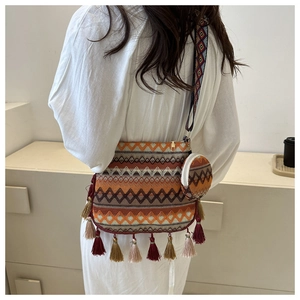 Détails d'un sac bandoulière bohème tissé avec motifs géométriques et pompons colorés
