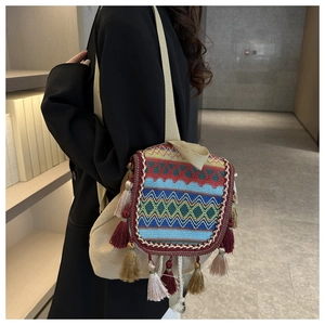 Détails de broderie géométrique et glands colorés sur un sac à dos tissé beige