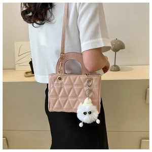 Detail view of pink quilted handbag with triangular stitching and plush mascot charm