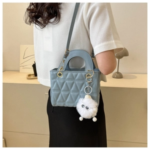 Detail of light blue quilted handbag with matte leather texture and white pompom charm