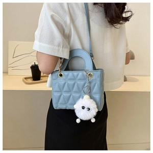 Detail of light blue quilted handbag with triangle pattern and a white plush charm