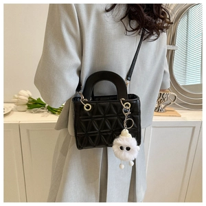 Black quilted crossbody bag with stylish furry monster charm shown on a model