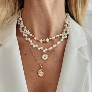 Collier à trois couches avec perles et pendentif cœur sur modèle en blazer blanc