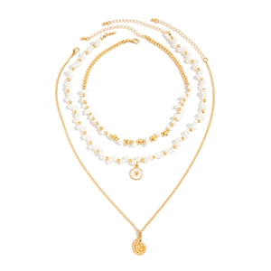 Ensemble de colliers bohèmes dorés avec perles, coquillages et pendentif cœur sur fond blanc