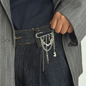 Detail of silver safety pin brooch with hanging chains and heart pendant on clothing