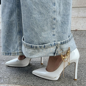 Detailed view of a gold tassel brooch pin used as a stylish accessory on denim pants cuff