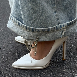 Silver safety pin with layered metal tassels and beads styled on denim cuffs