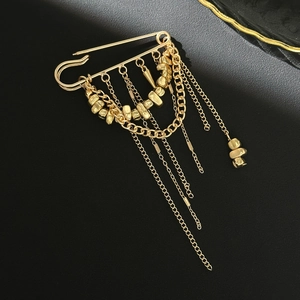 Detail of a golden tassel safety pin brooch with hanging metal chains and spikes