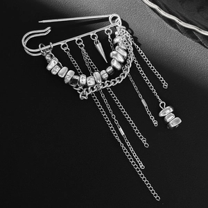 Detail of silver safety pin brooch with punk tassels and irregular metallic beads