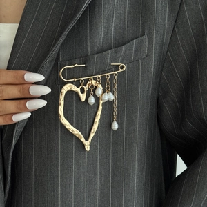Golden heart pendant brooch with teardrop pearls and safety pin design on a blazer